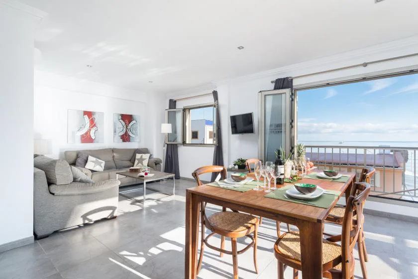 A bright living and dining area opens onto a balcony with a sea view.