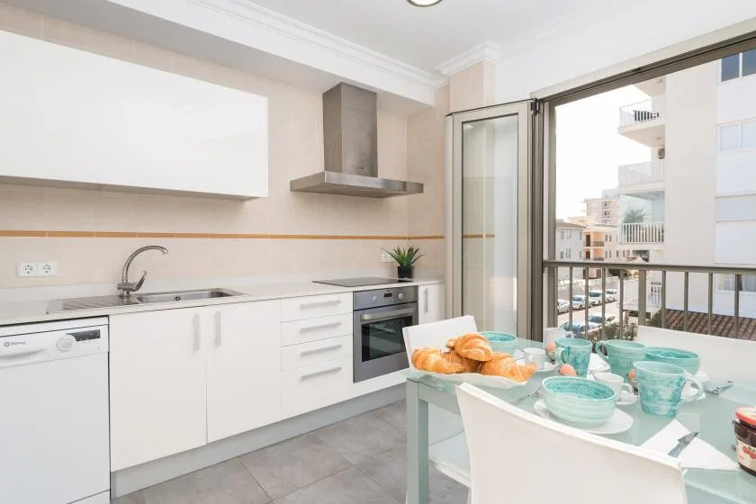 A bright kitchen with white cabinets and a dining table set with dishes.