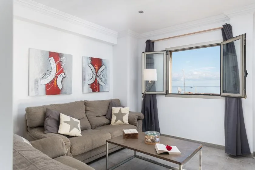 A bright living room with seating, a coffee table, and an open window.