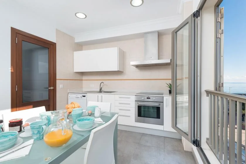 A bright kitchen with white cabinets and a dining table set with dishes.