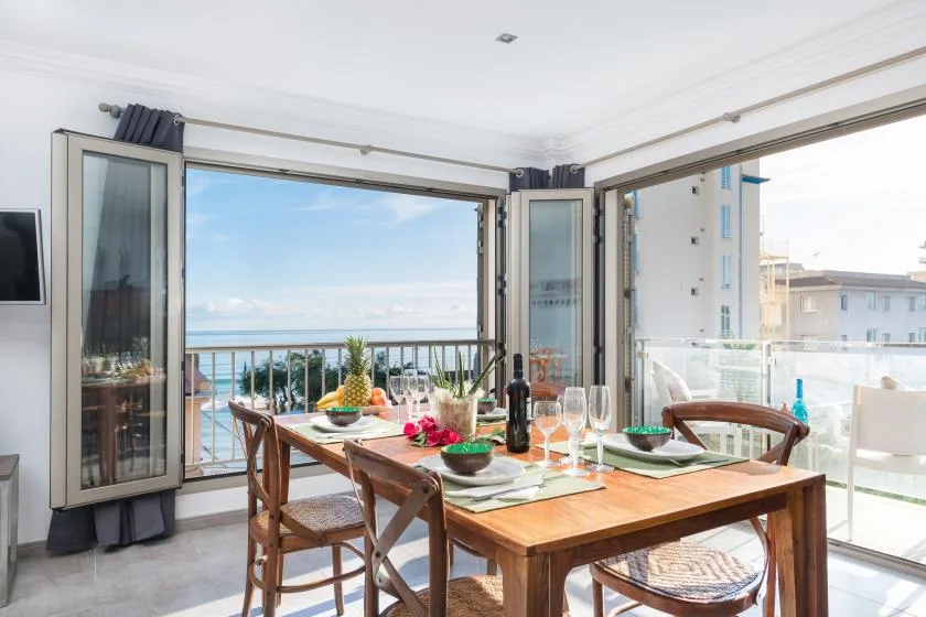 A dining area opens onto a balcony with a view of the sea.