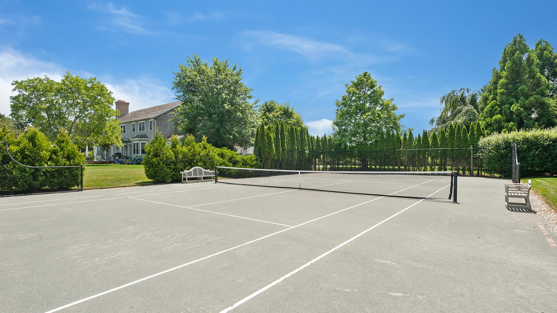 Una pista de tenis al aire libre con una red, rodeada de vegetación.