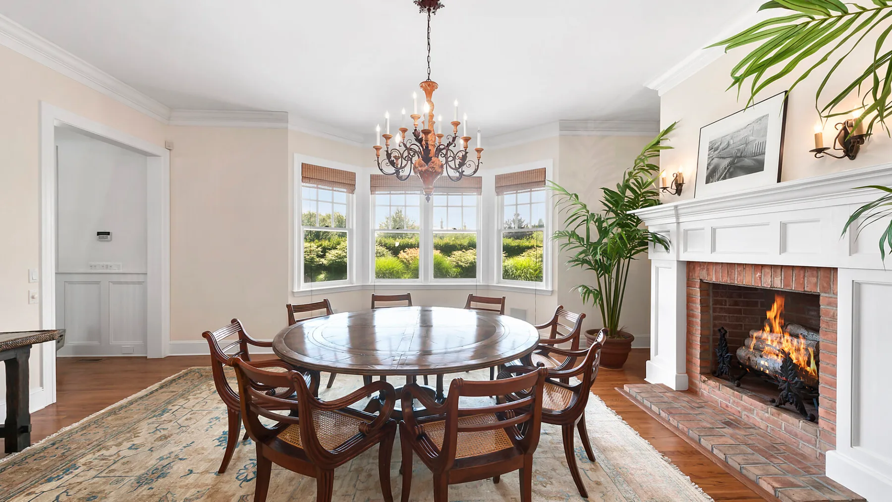 A dining room with a round table and chairs beside a fireplace.