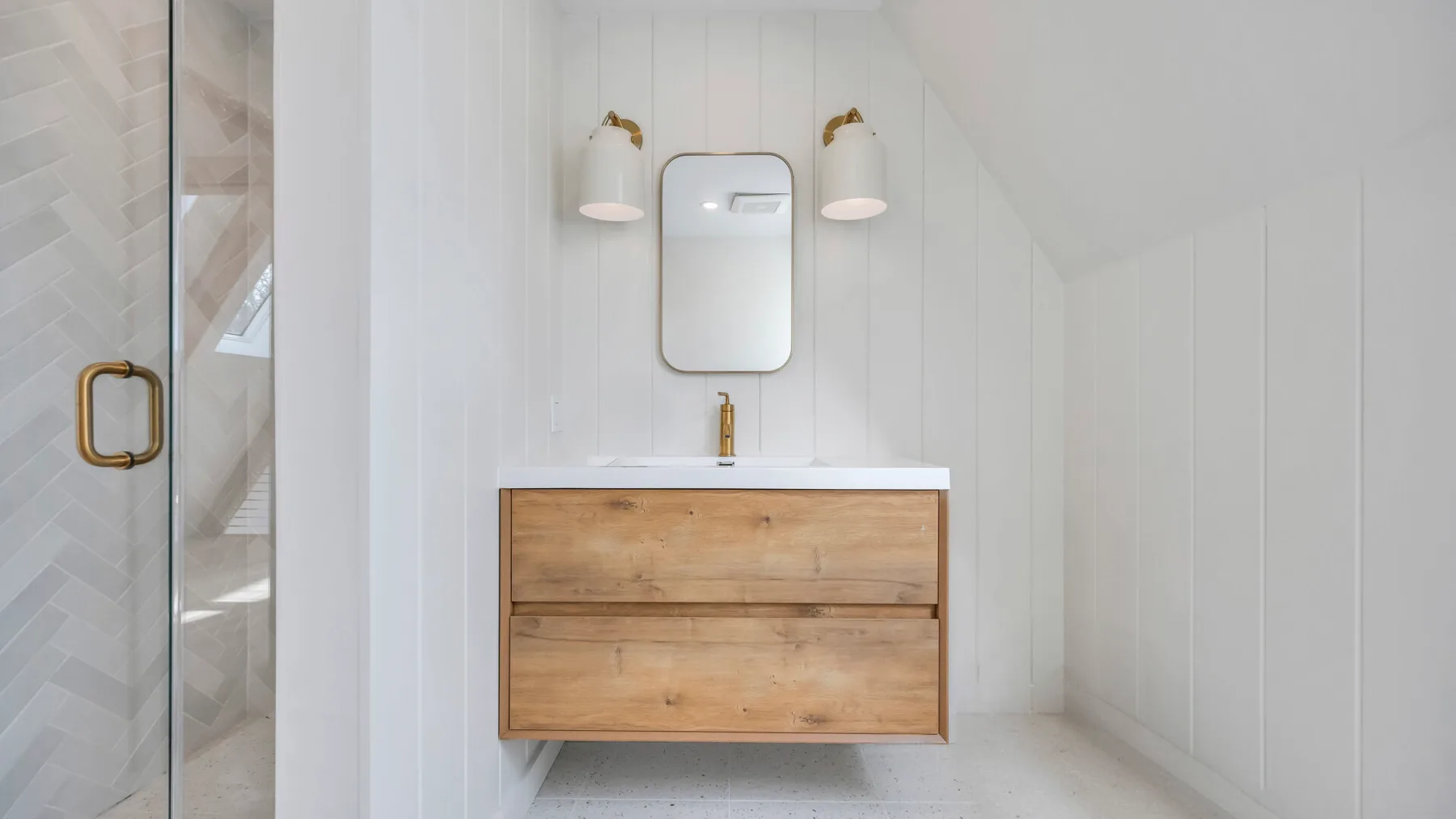 A bright bathroom with a wooden vanity and wall mirror.