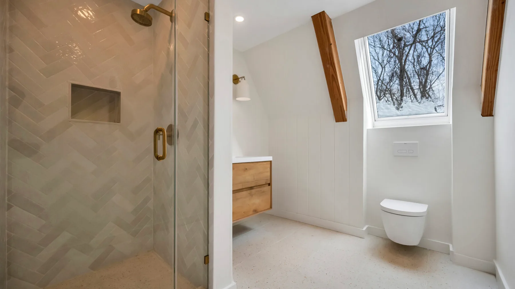 A bright bathroom with a glass shower and a window above a wall-mounted toilet.