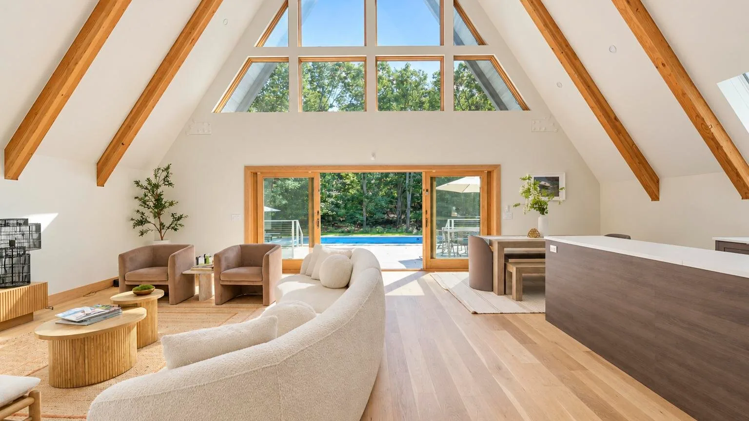 A bright open-plan living area has a curved seating arrangement and large windows.