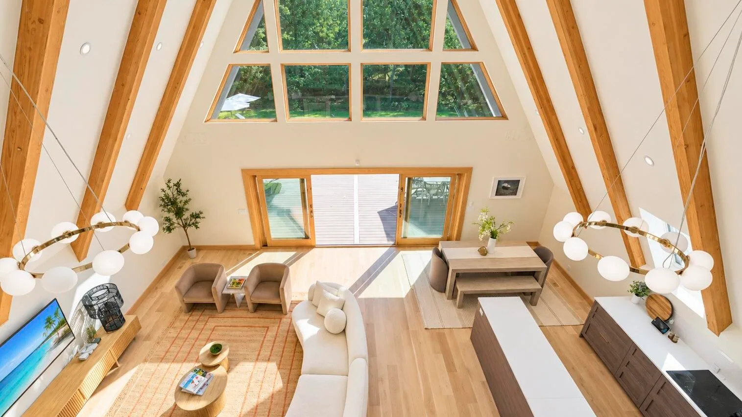 A-frame living room with tall windows, seating, and a dining table.