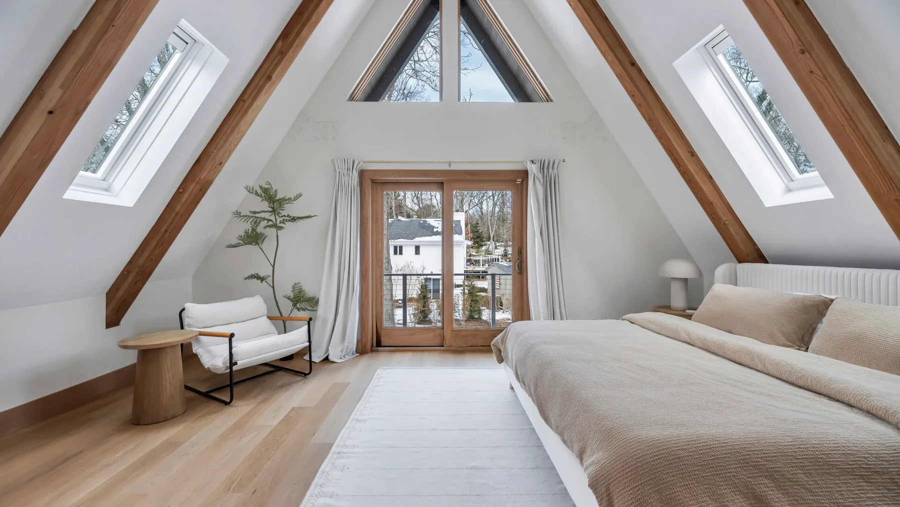 A bright attic bedroom with a bed beneath sloped ceilings and skylights.