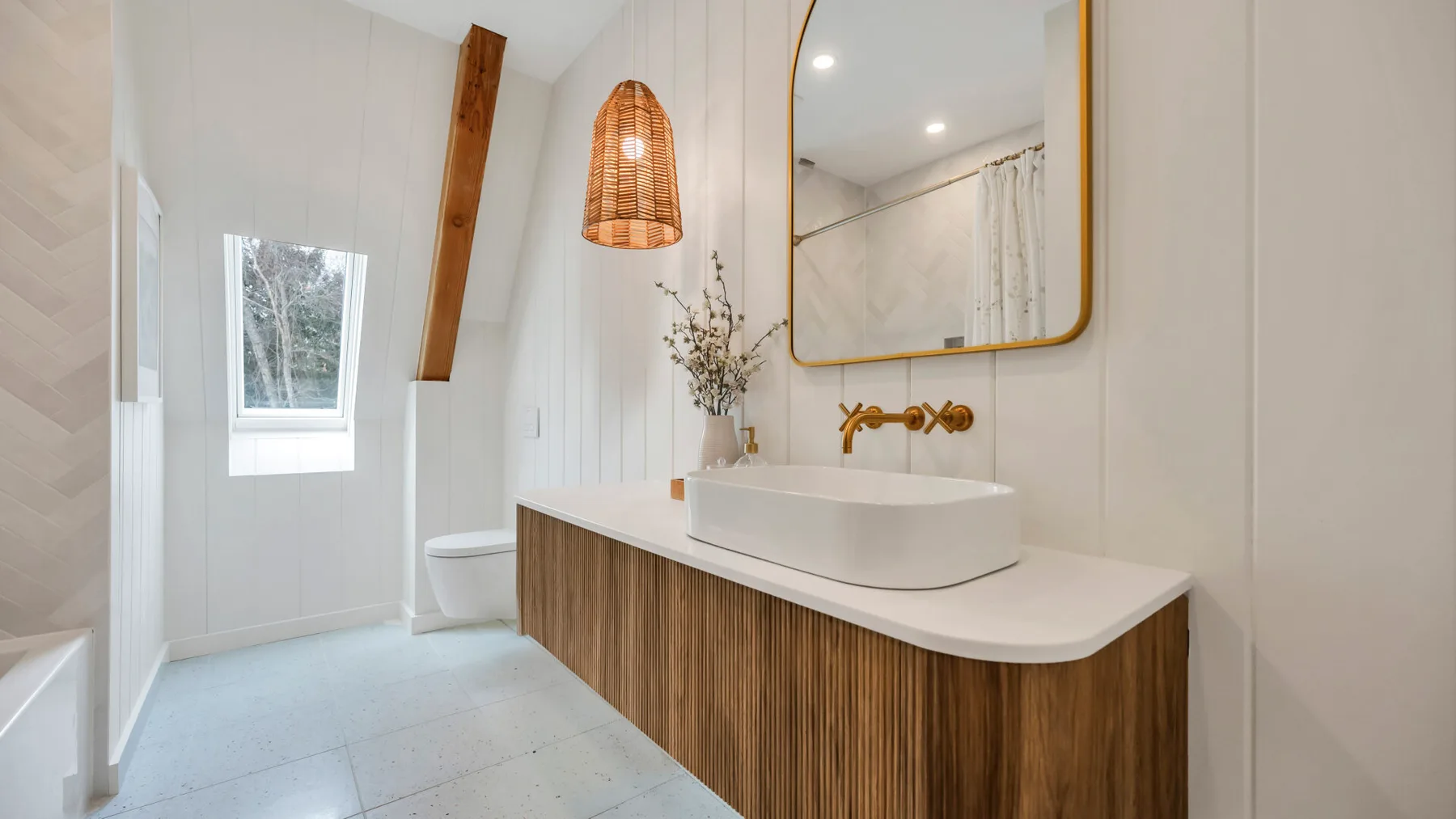 A bright bathroom with a long vanity, vessel sink, and large mirror.