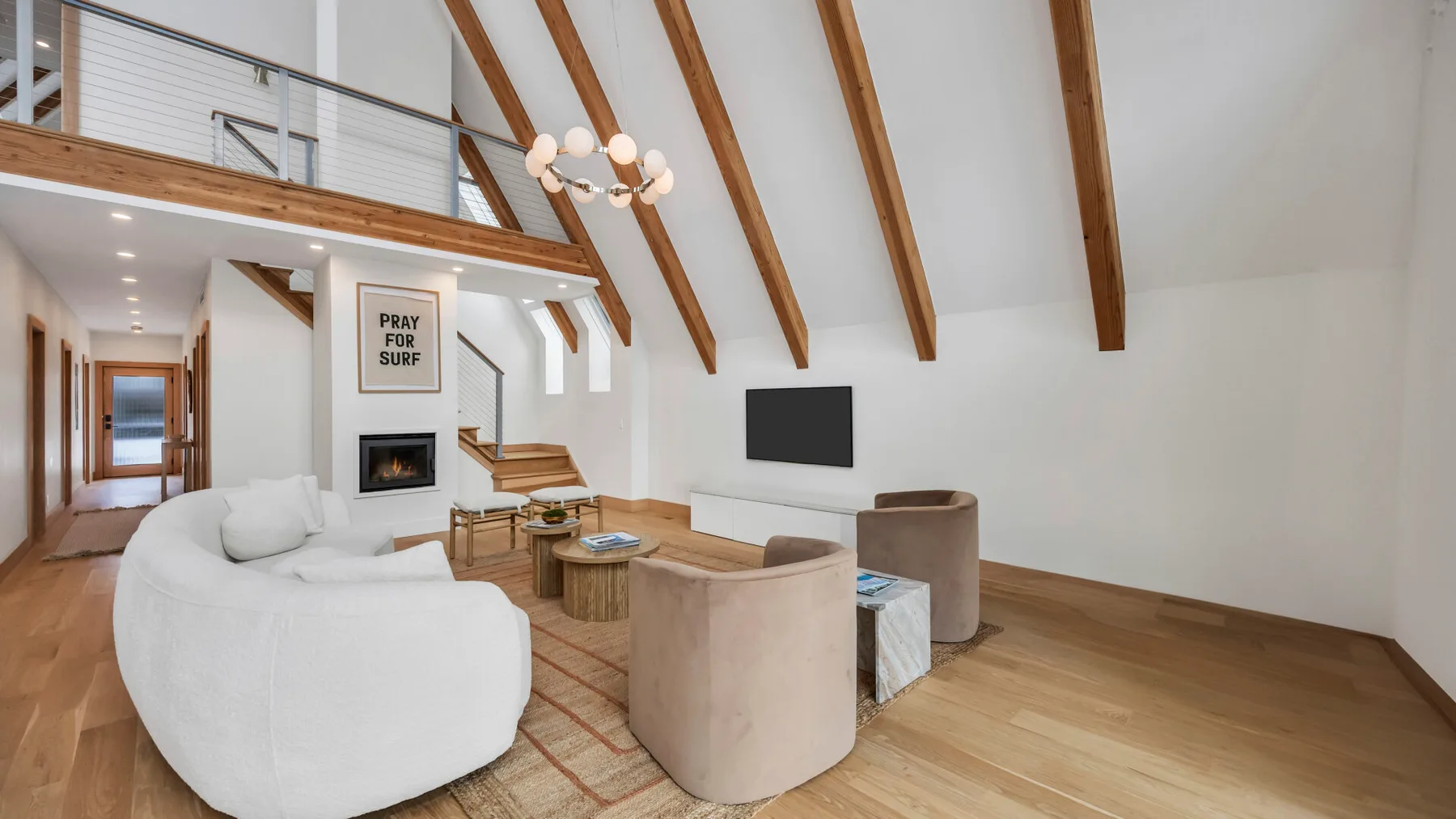 A bright living room with a high timber-beamed ceiling and a seating area.