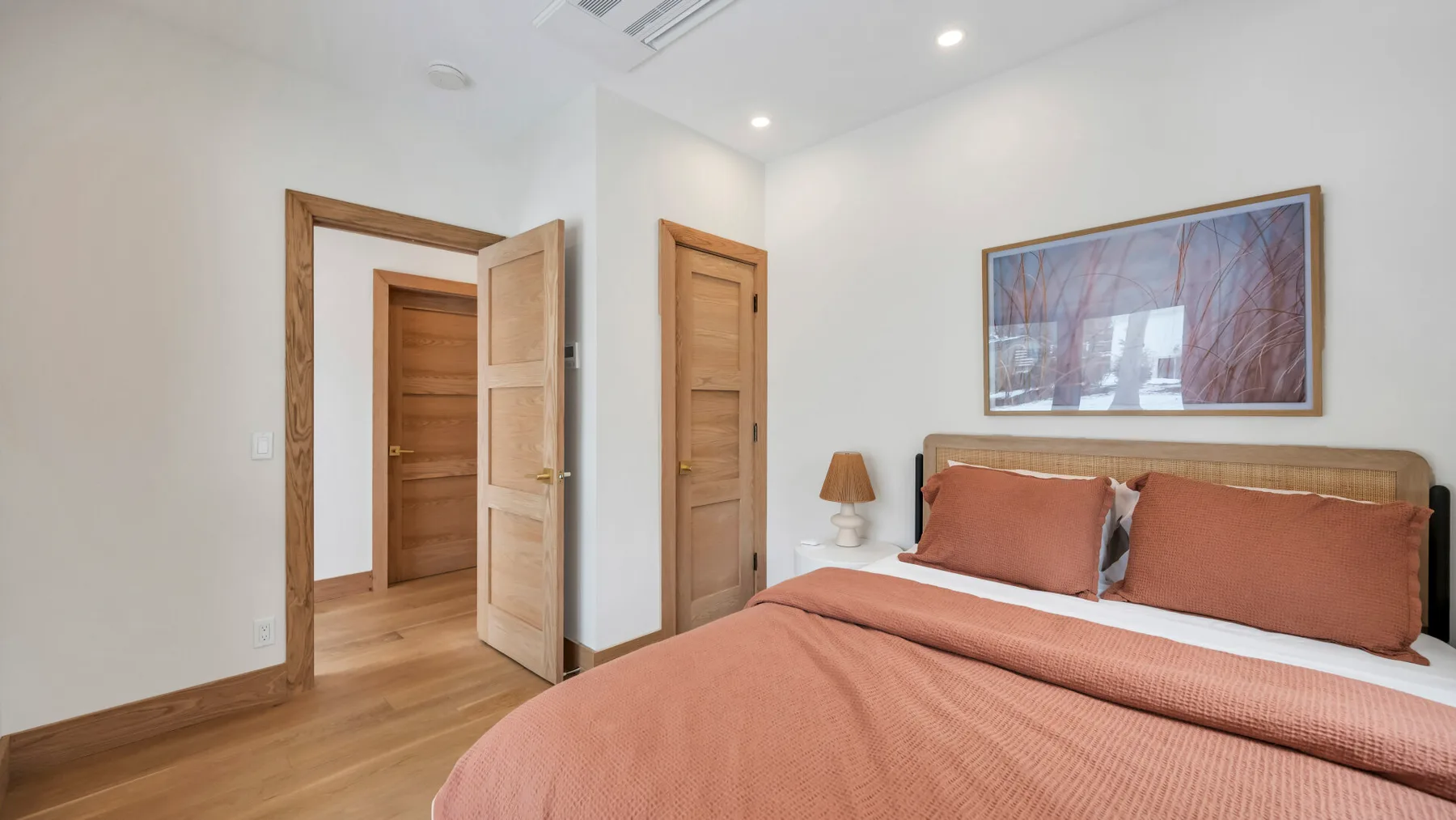 A bedroom with a neatly made bed and a framed picture above it.