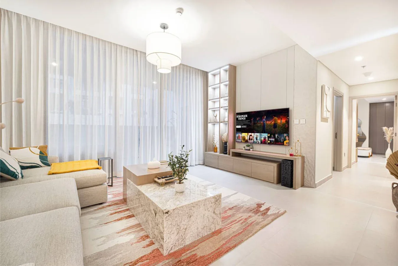 Una sala luminosa con asientos, una mesa de centro de mármol y un televisor.