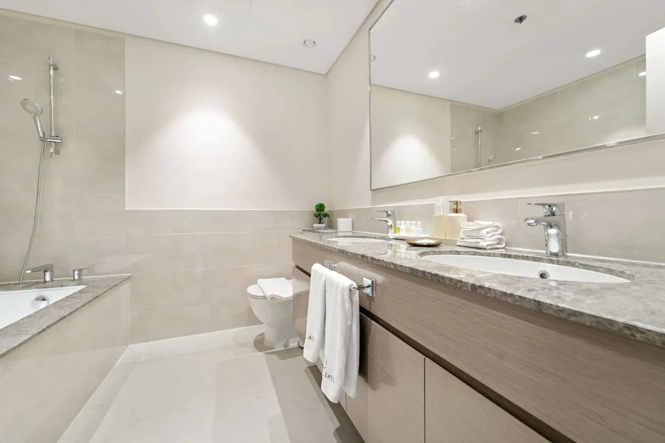 Un baño luminoso con un lavabo largo, espejo y bañera.