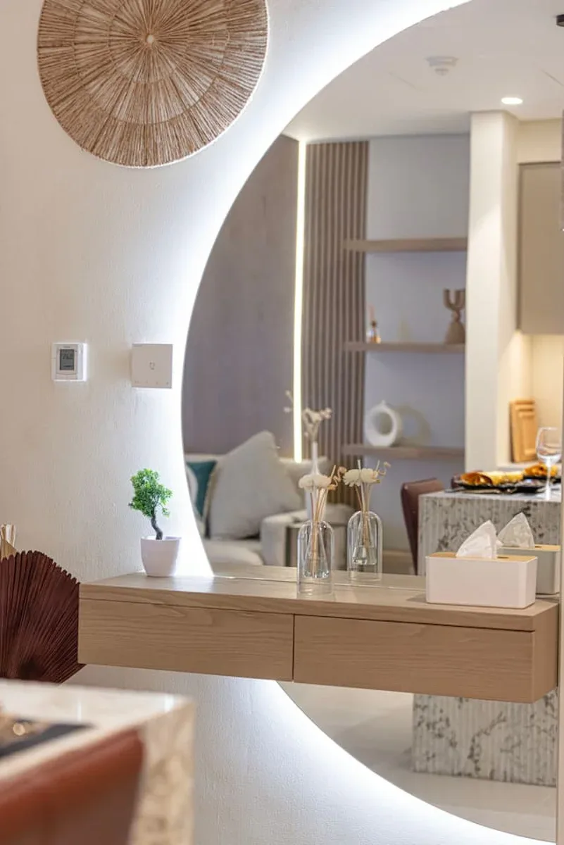 Un interior moderno y luminoso con una consola flotante de madera y estantes decorativos.