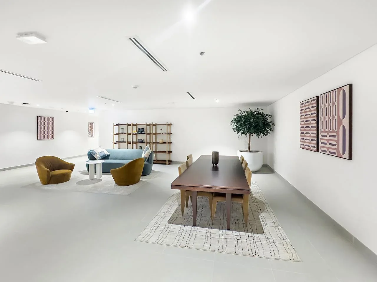 Una sala luminosa con una mesa larga, asientos bajos y arte en las paredes.