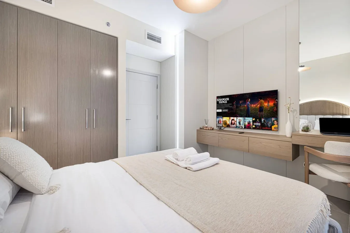 Un dormitorio con cama, armarios empotrados y un televisor sobre un escritorio.