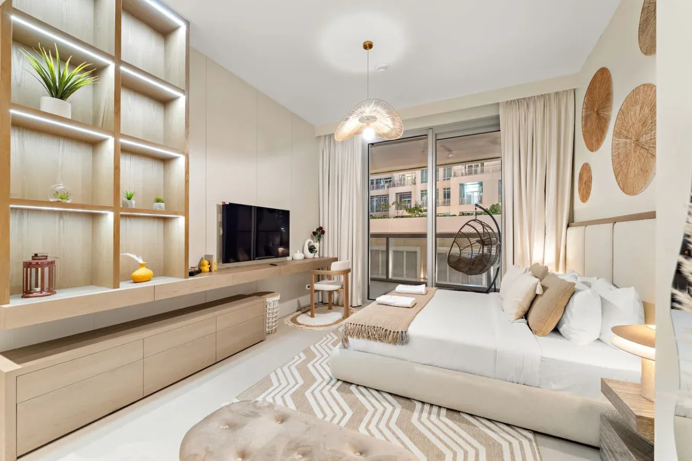Un dormitorio luminoso tiene una cama junto a una ventana grande y estanterías empotradas.
