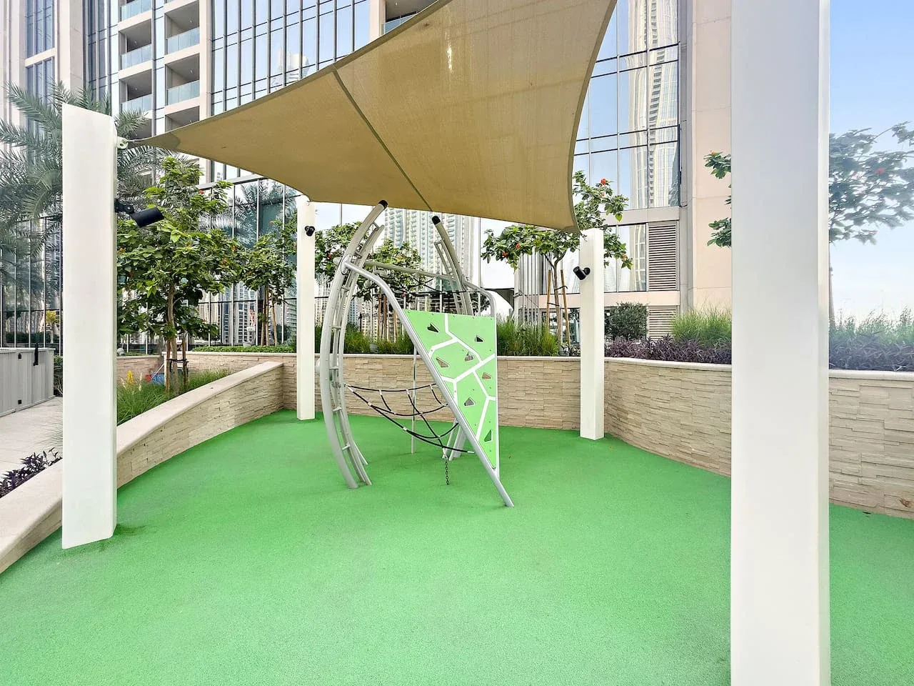 Área de juegos al aire libre con suelo verde y equipo para trepar.