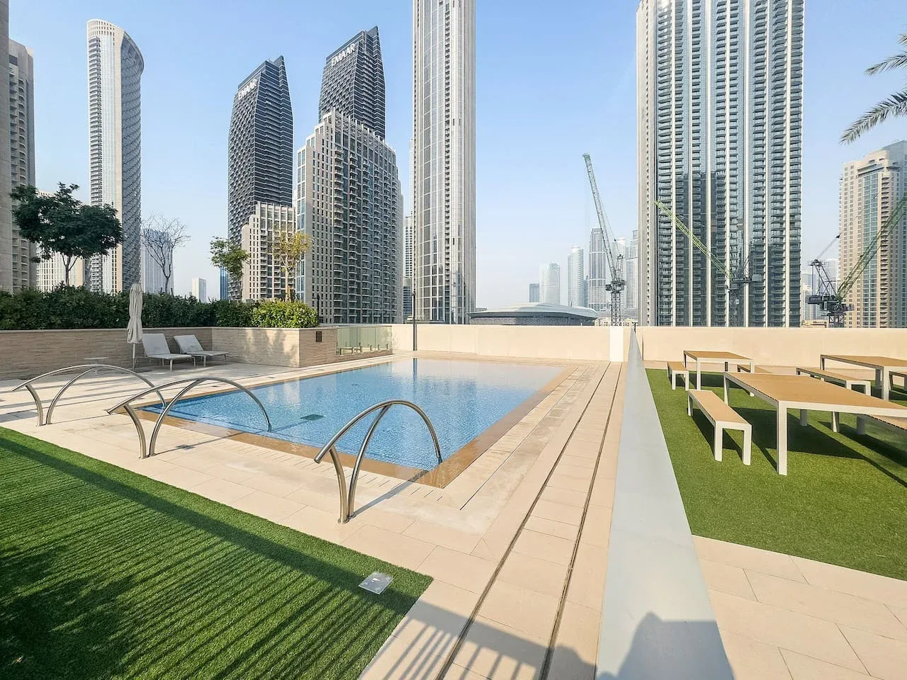 Una piscina en la azotea y una zona de asientos al aire libre dan a varios edificios altos.