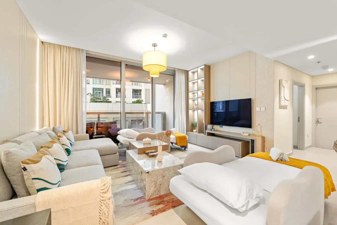 Una sala luminosa con zona de estar, televisor y ventanales.