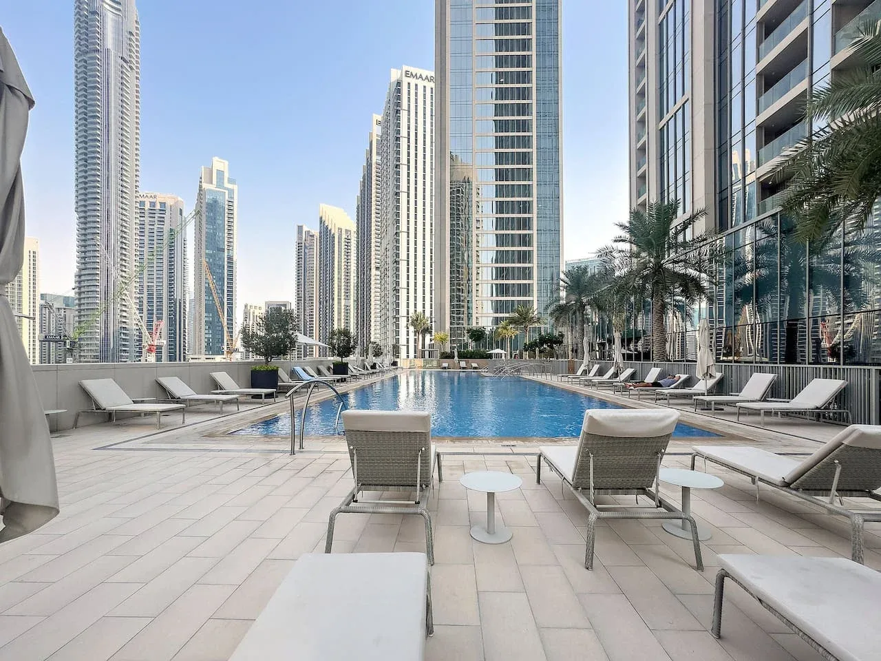 Una piscina al aire libre rodeada de asientos de descanso y edificios altos.
