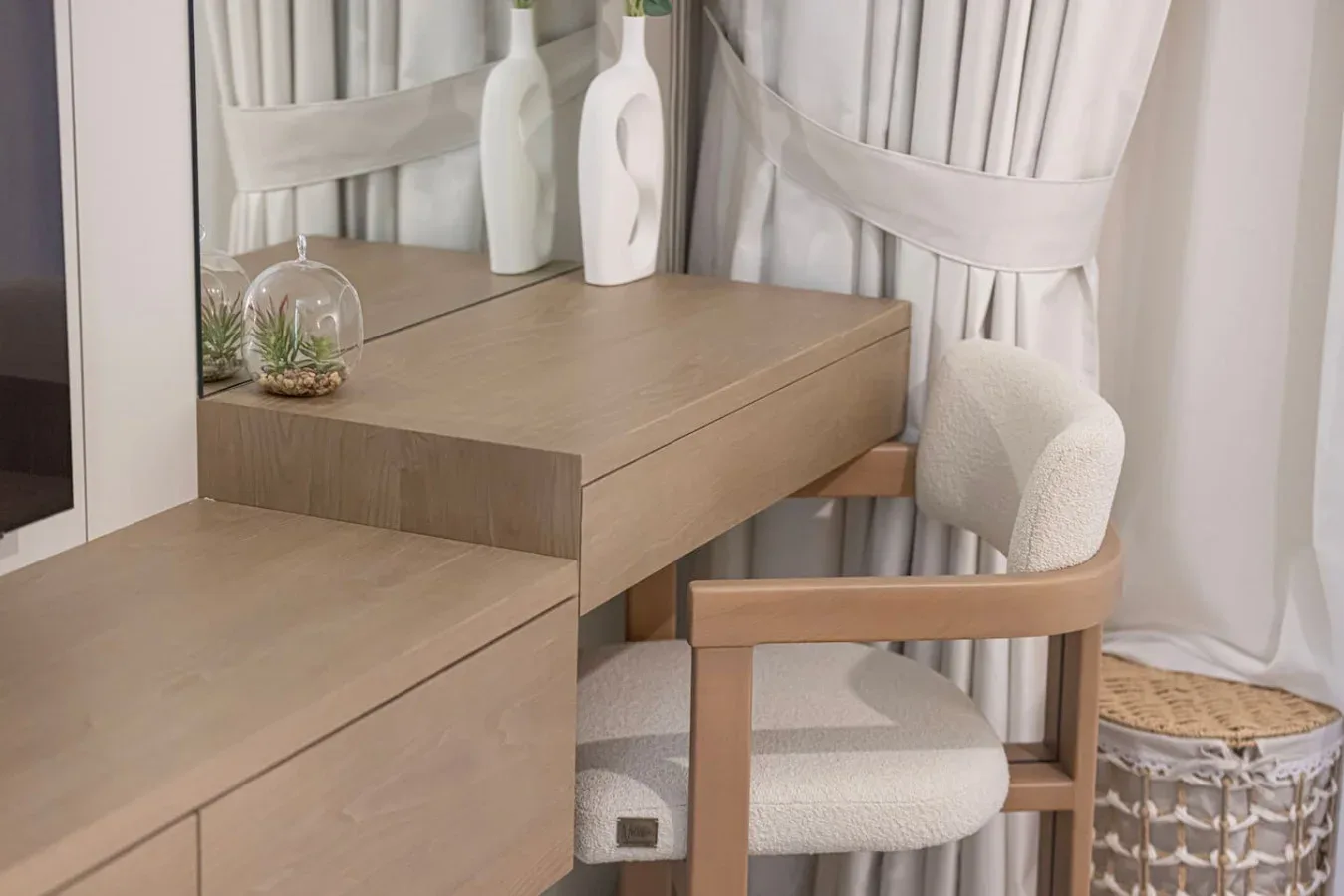 Un tocador de dormitorio con una mesa de madera, una silla acolchada y cortinas.