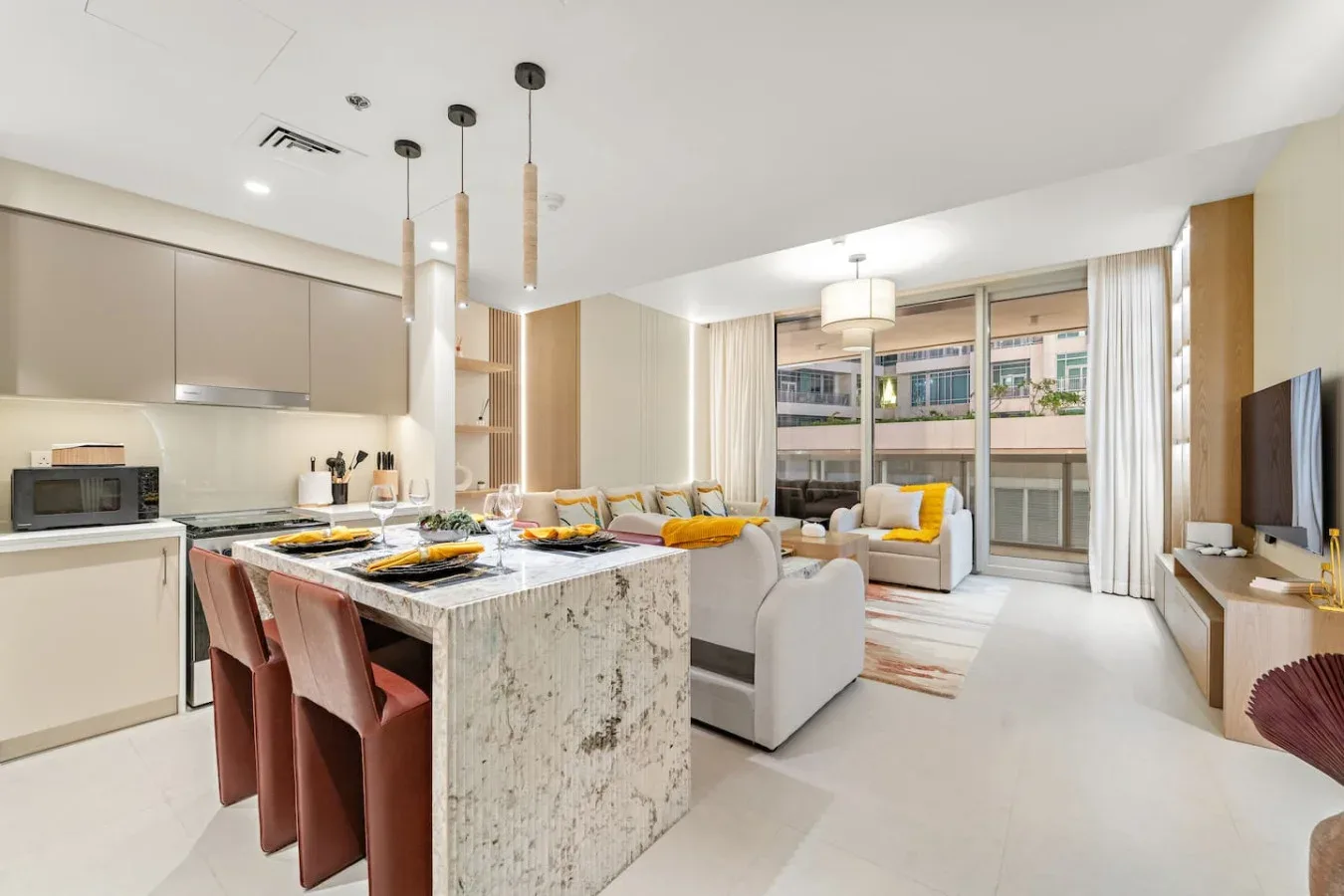 Sala de estar y cocina abiertas, con una isla de mármol y asientos.