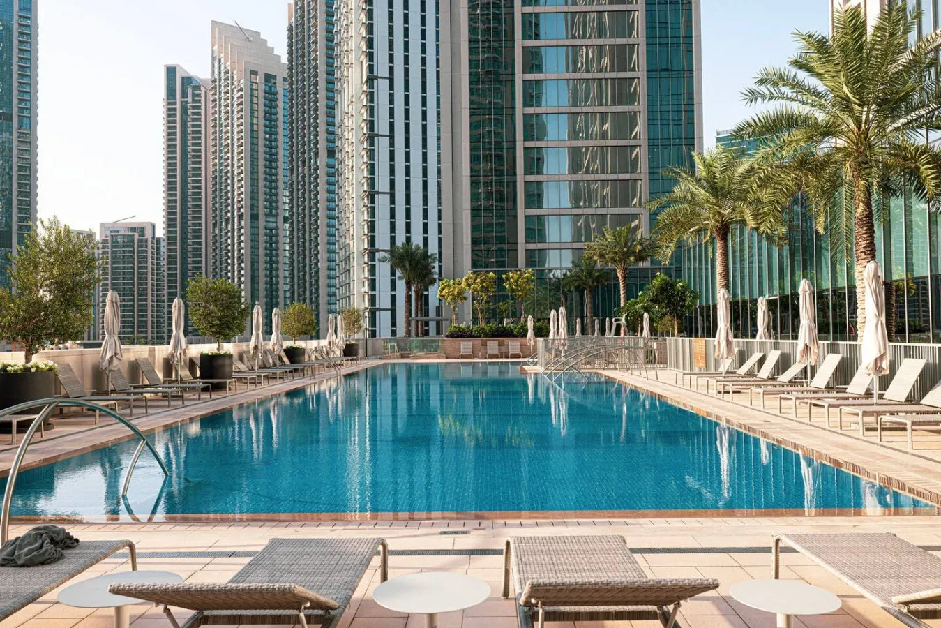 Una piscina al aire libre está rodeada de asientos y edificios altos.