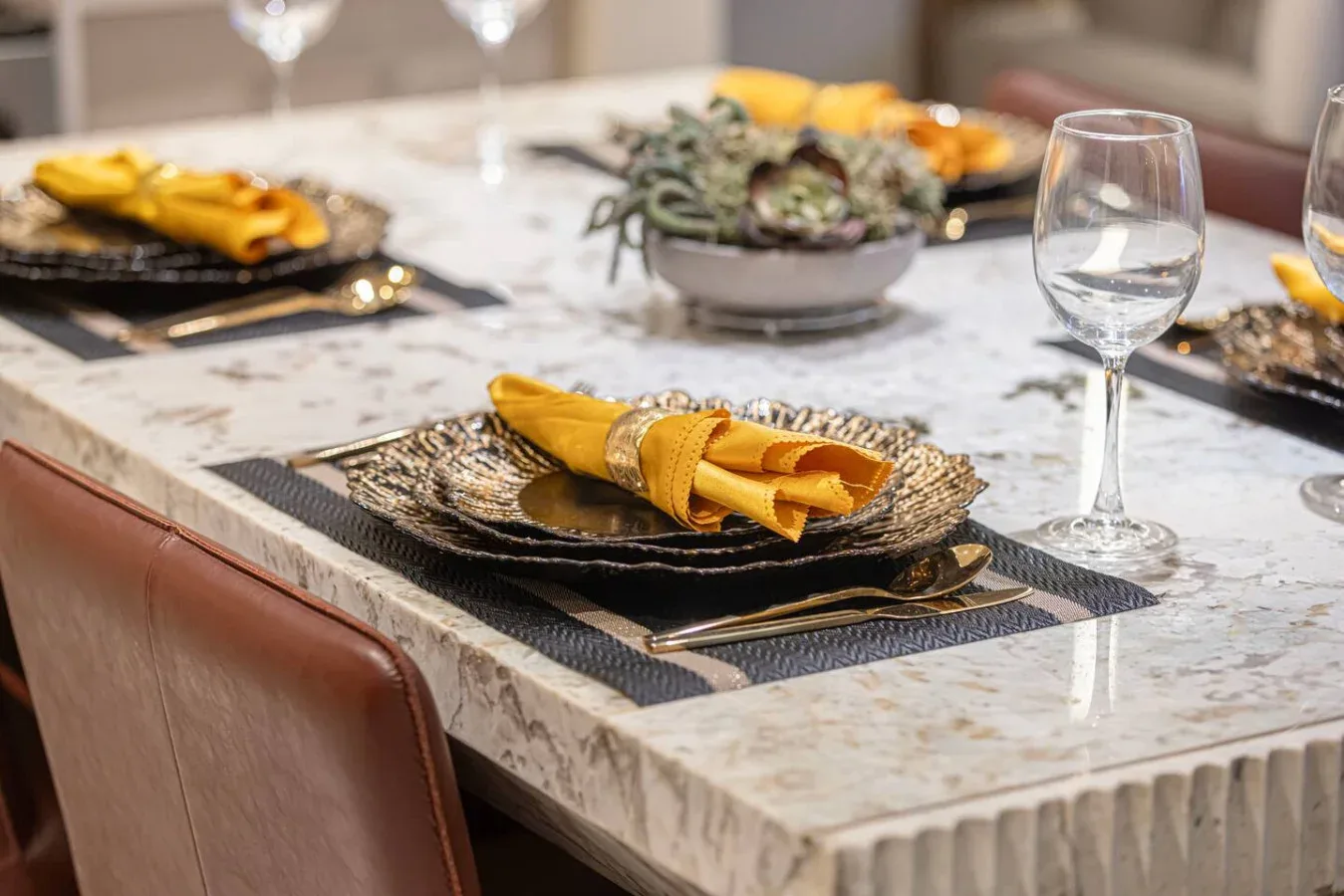 Una mesa de comedor está puesta con platos, servilletas dobladas y cristalería.