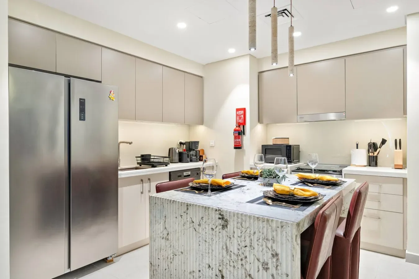 A modern kitchen with an island, cooking appliances, and bar seating.