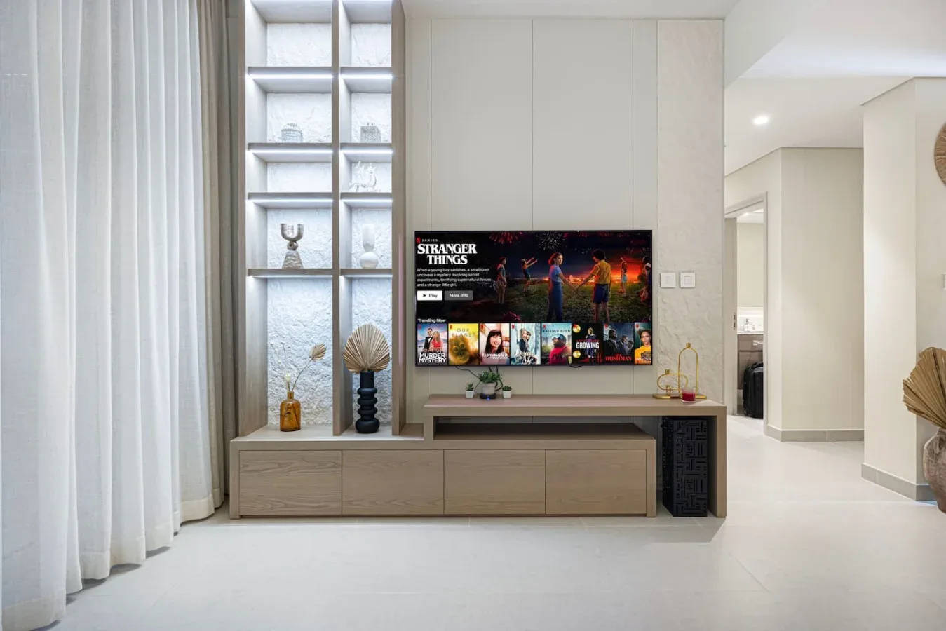 Una sala luminosa con un televisor integrado en un mueble de pared.