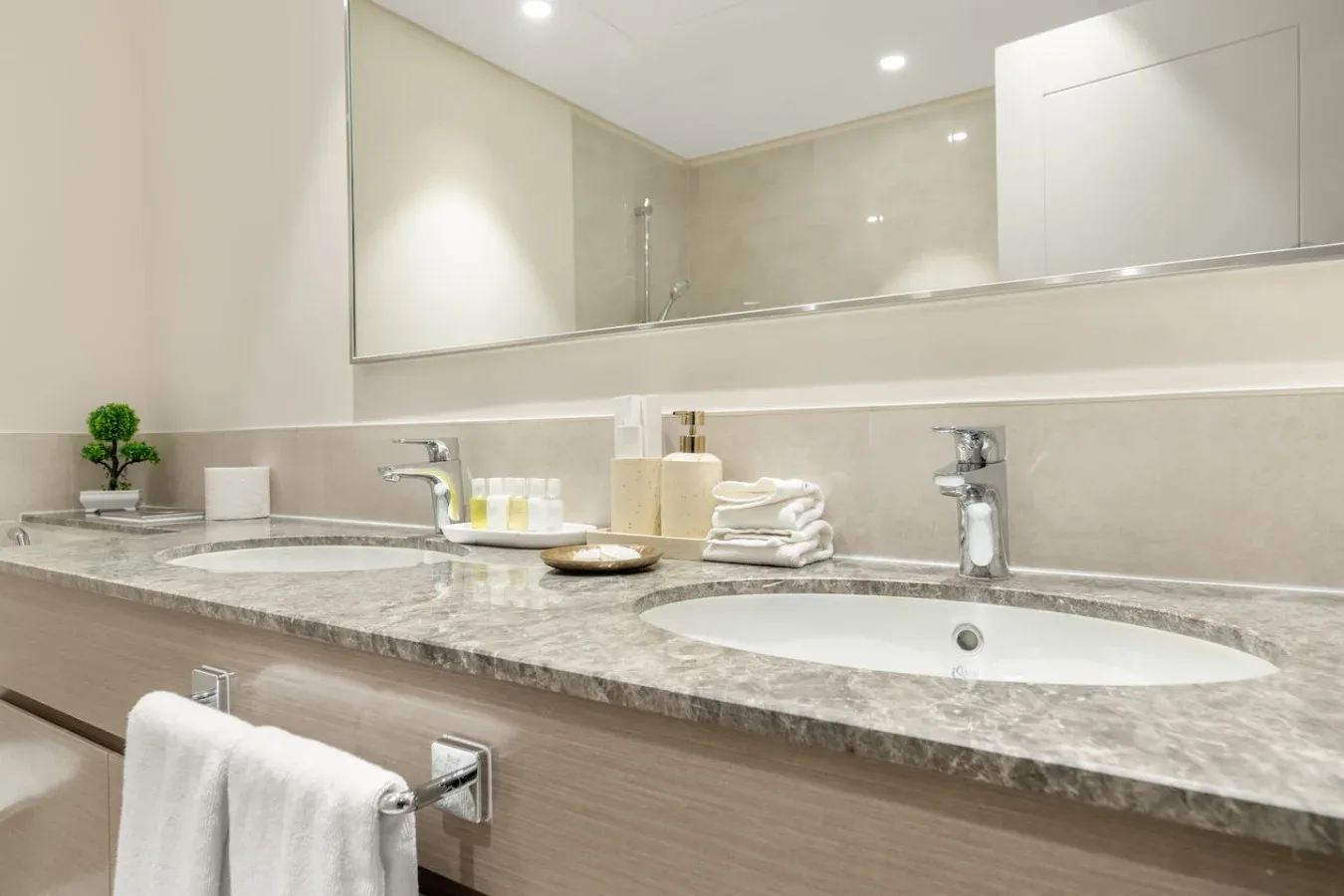 Un tocador de baño con dos lavabos, toallas dobladas y un espejo grande.
