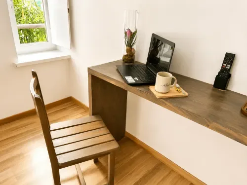 Escritorio de madera con un ordenador portátil, café y vistas desde la ventana.