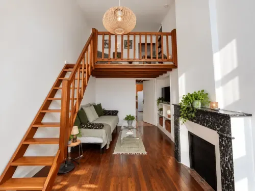 Suite con entreplanta, escalera de madera, chimenea y zona de estar.