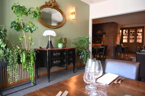 Zona de comedor con paredes verdes, plantas y vistas al jardín.