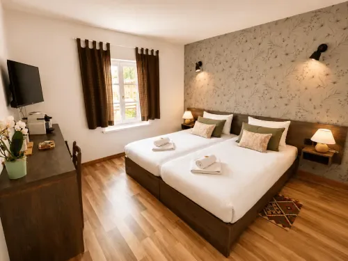 Habitación con dos camas, vistas al jardín y escritorio de madera.