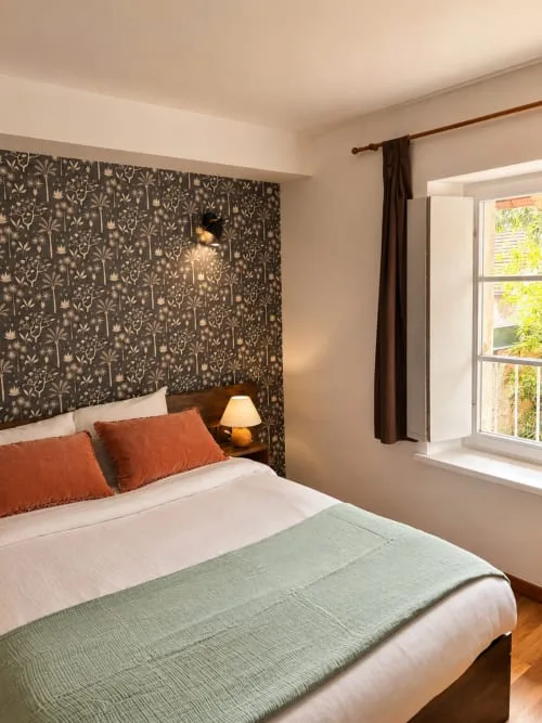 Habitación doble con cabecero floral y vistas al jardín.