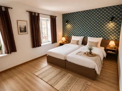 Habitación con dos camas, ropa de cama blanca y cabecero estampado.
