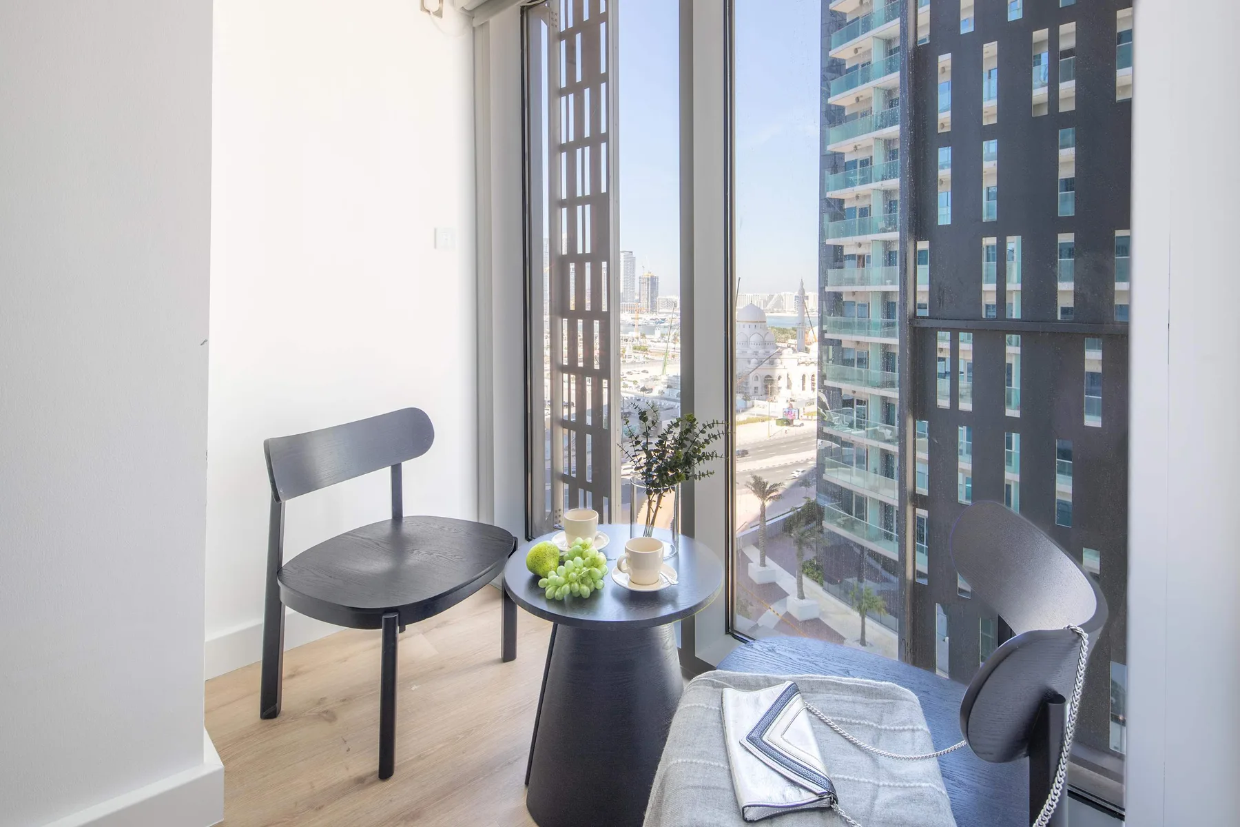 Una luminosa zona de estar junto a ventanas altas, con asientos y una mesa pequeña.