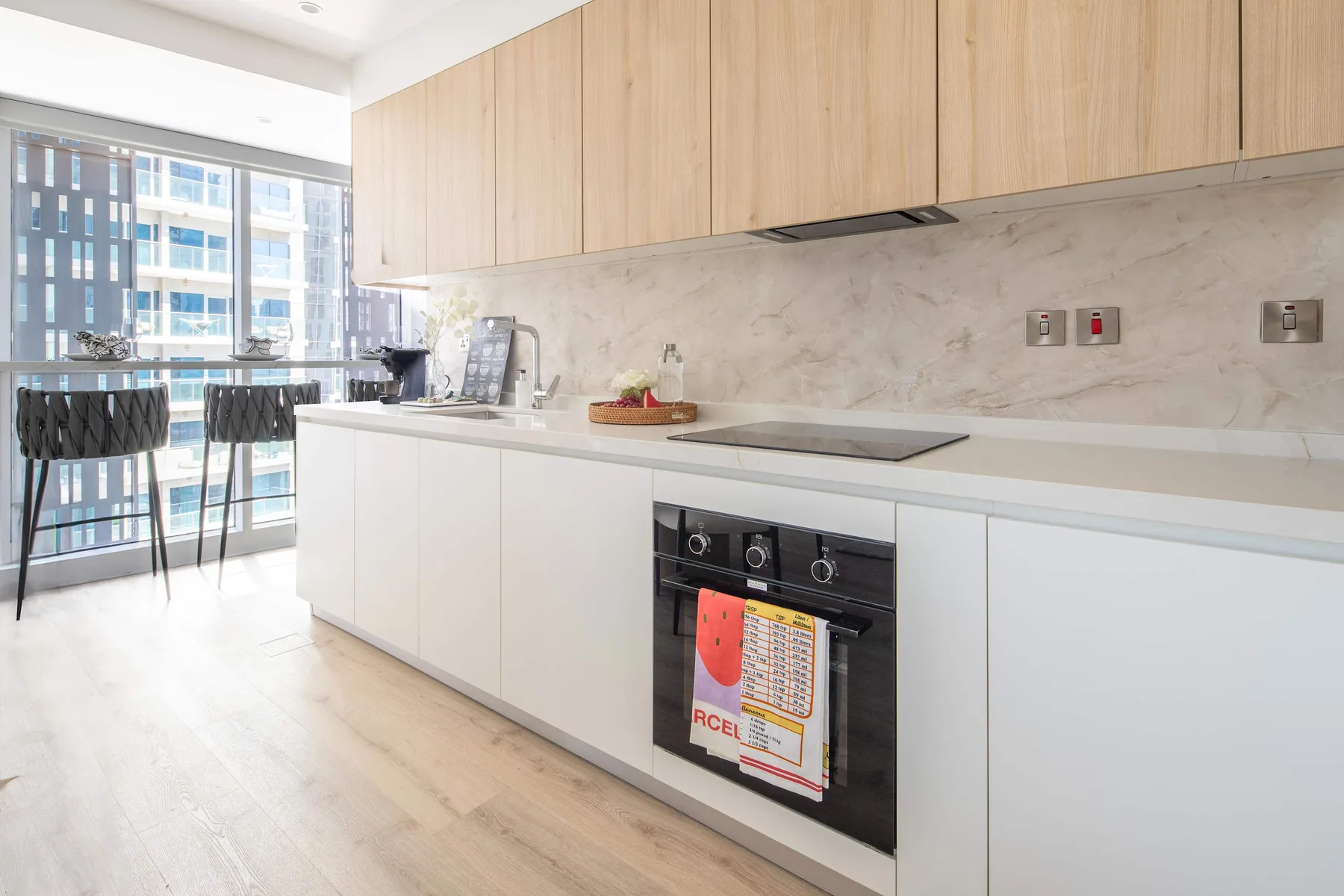 Una cocina moderna con gabinetes de madera clara, una encimera y un comedor junto a la ventana.