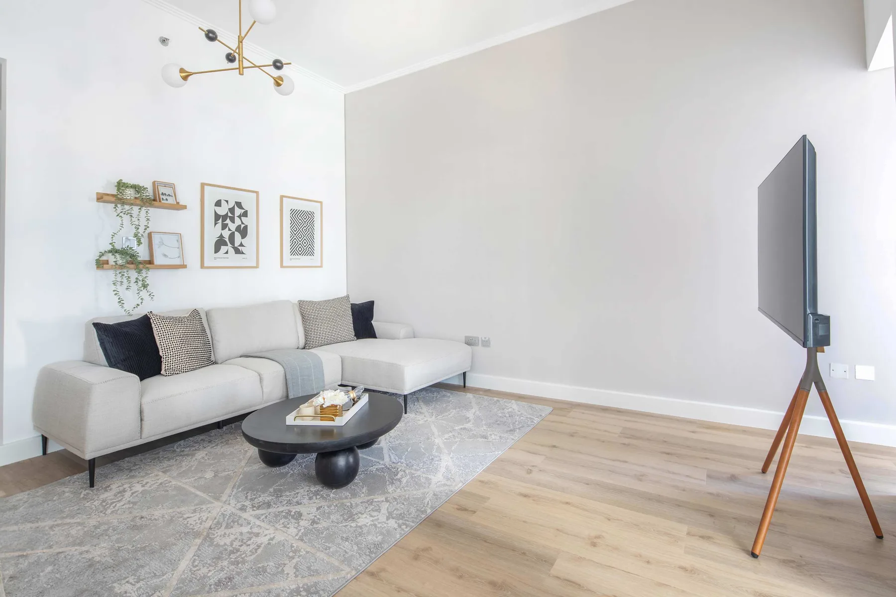 Una sala luminosa con una zona de asientos seccional y un televisor.