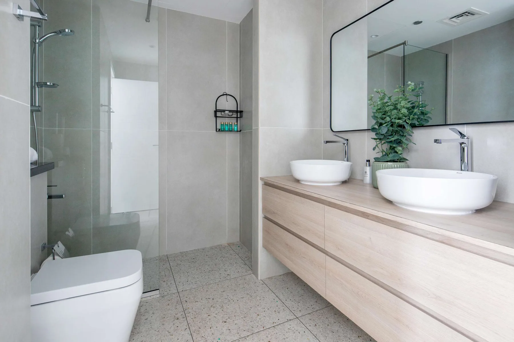 Un baño moderno con ducha a ras de suelo y un tocador con dos lavabos.