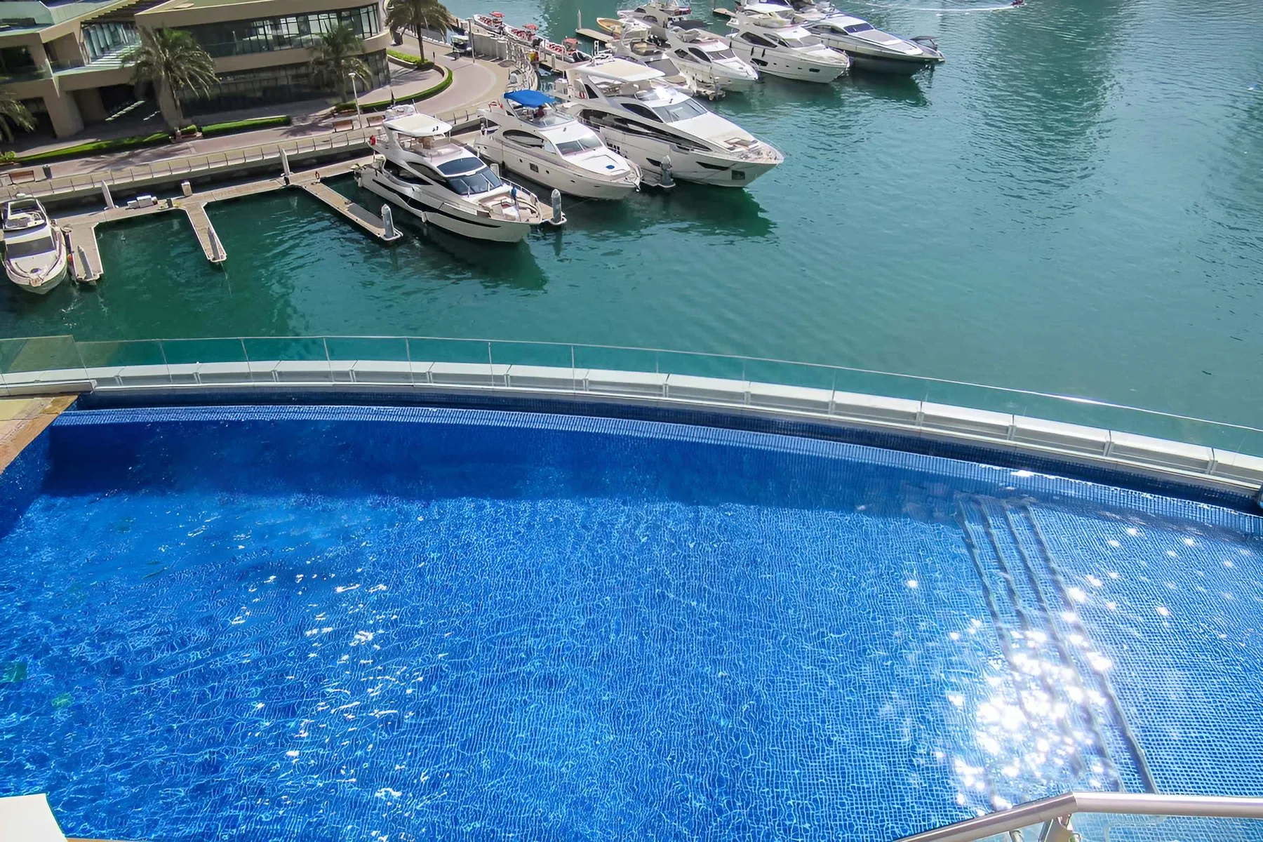 Una piscina azul tiene vistas a una marina llena de barcos.