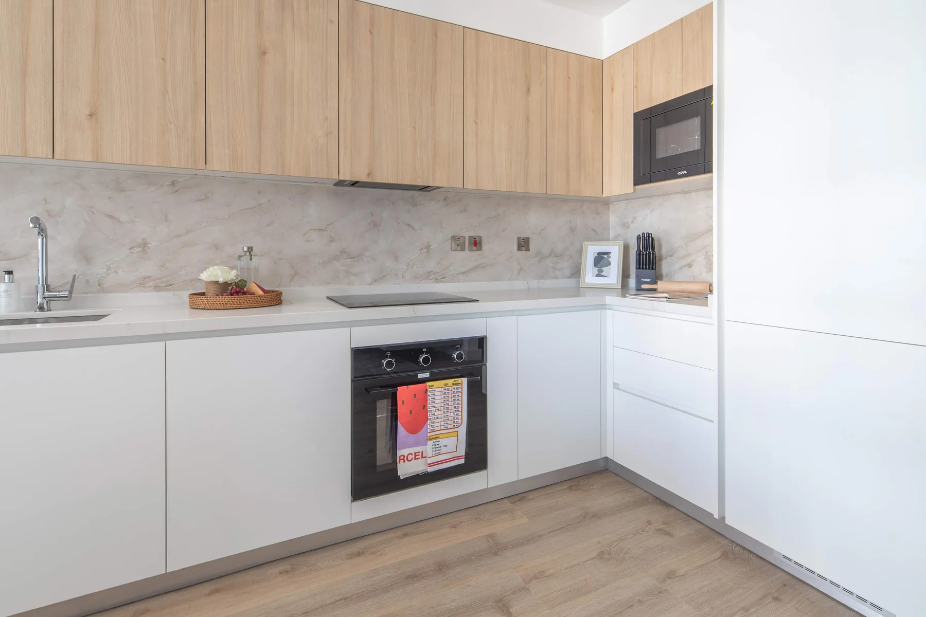 Una cocina luminosa con armarios de madera clara y un horno integrado.