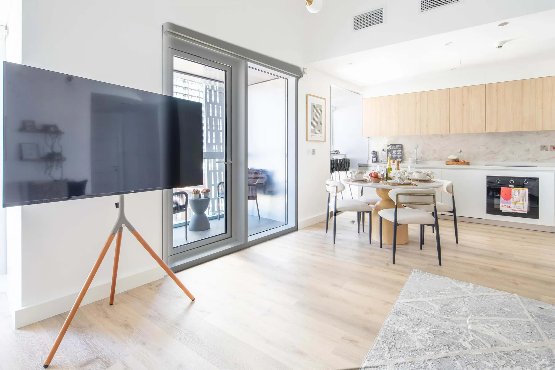 Una luminosa sala-comedor de concepto abierto con televisor y cocina.