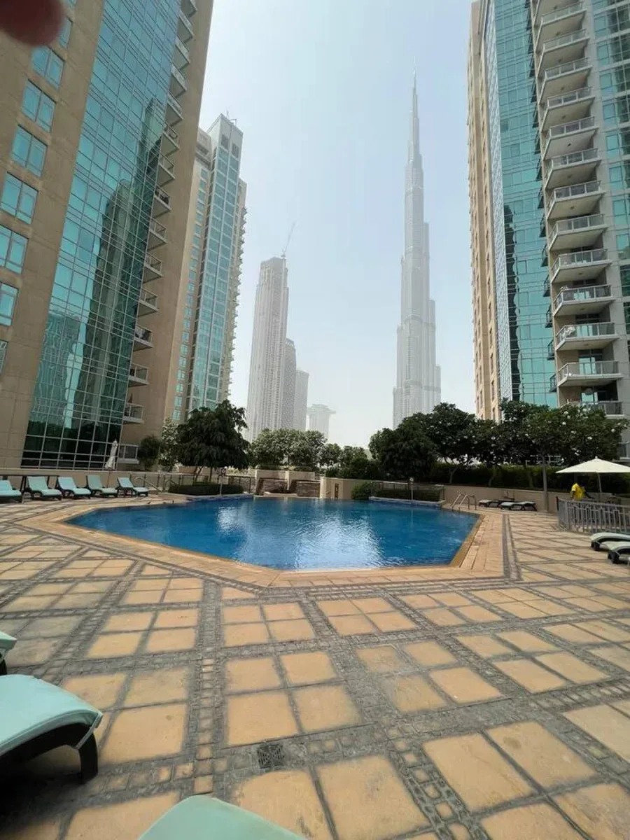 Una piscina y una terraza de baldosas están rodeadas de edificios altos.