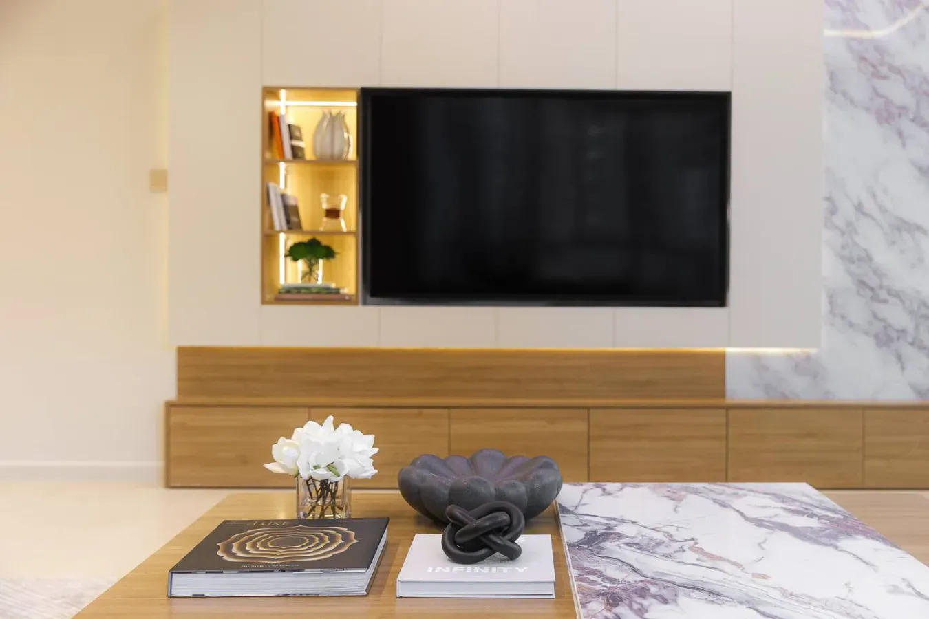 Una sala de estar con un televisor montado en la pared sobre un mueble de madera.