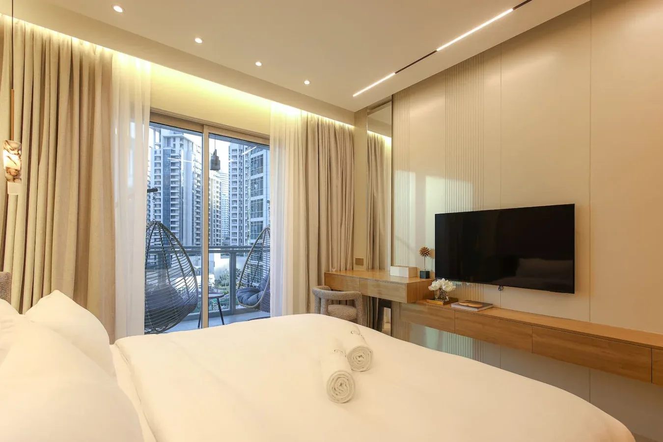 Un dormitorio con una cama grande, un televisor y cortinas de suelo a techo.