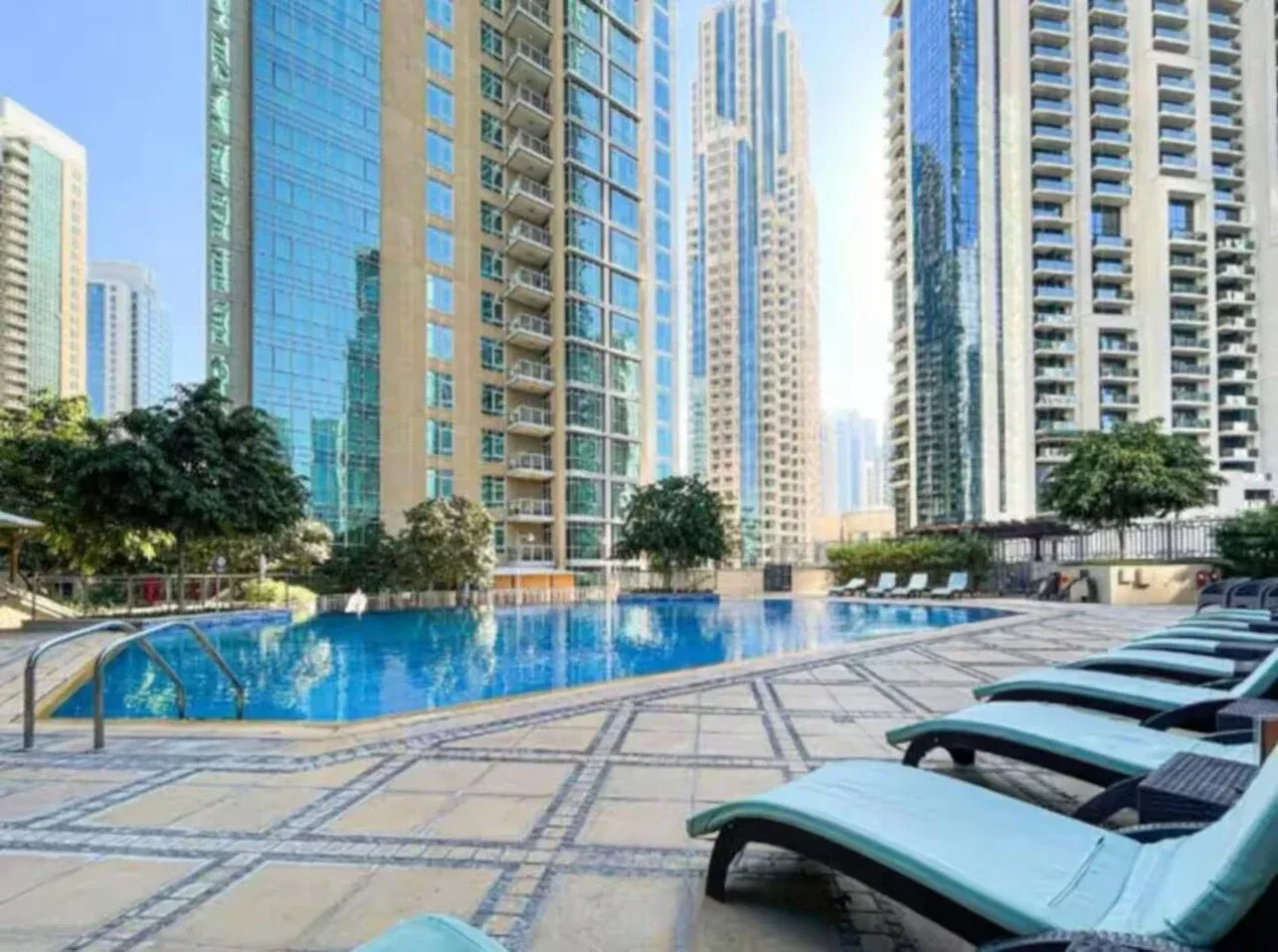 Una piscina al aire libre está rodeada de altos edificios residenciales y asientos reclinables.