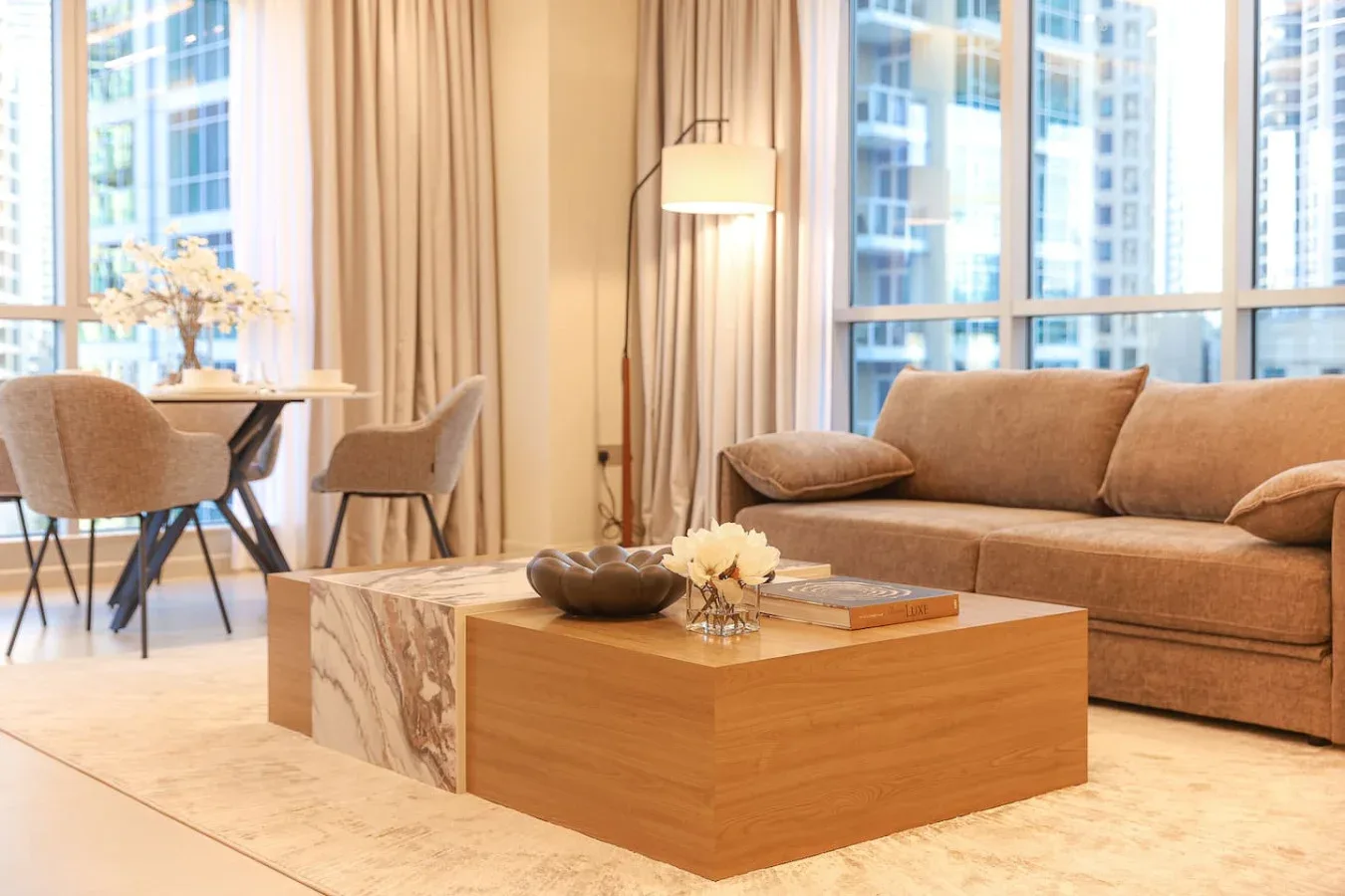 Una sala de estar con asientos alrededor de una mesa baja junto a grandes ventanas.